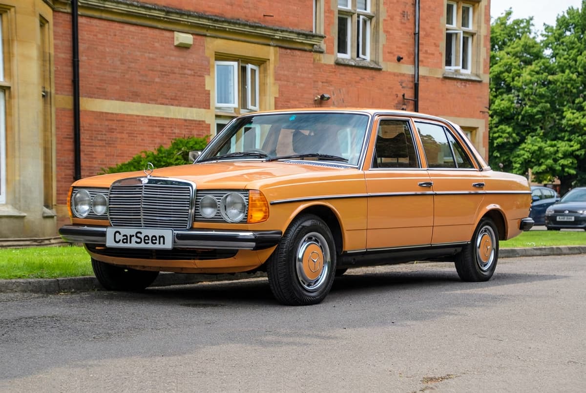 Orange Mercedes-Benz W123 saloon outside a red-brick country house