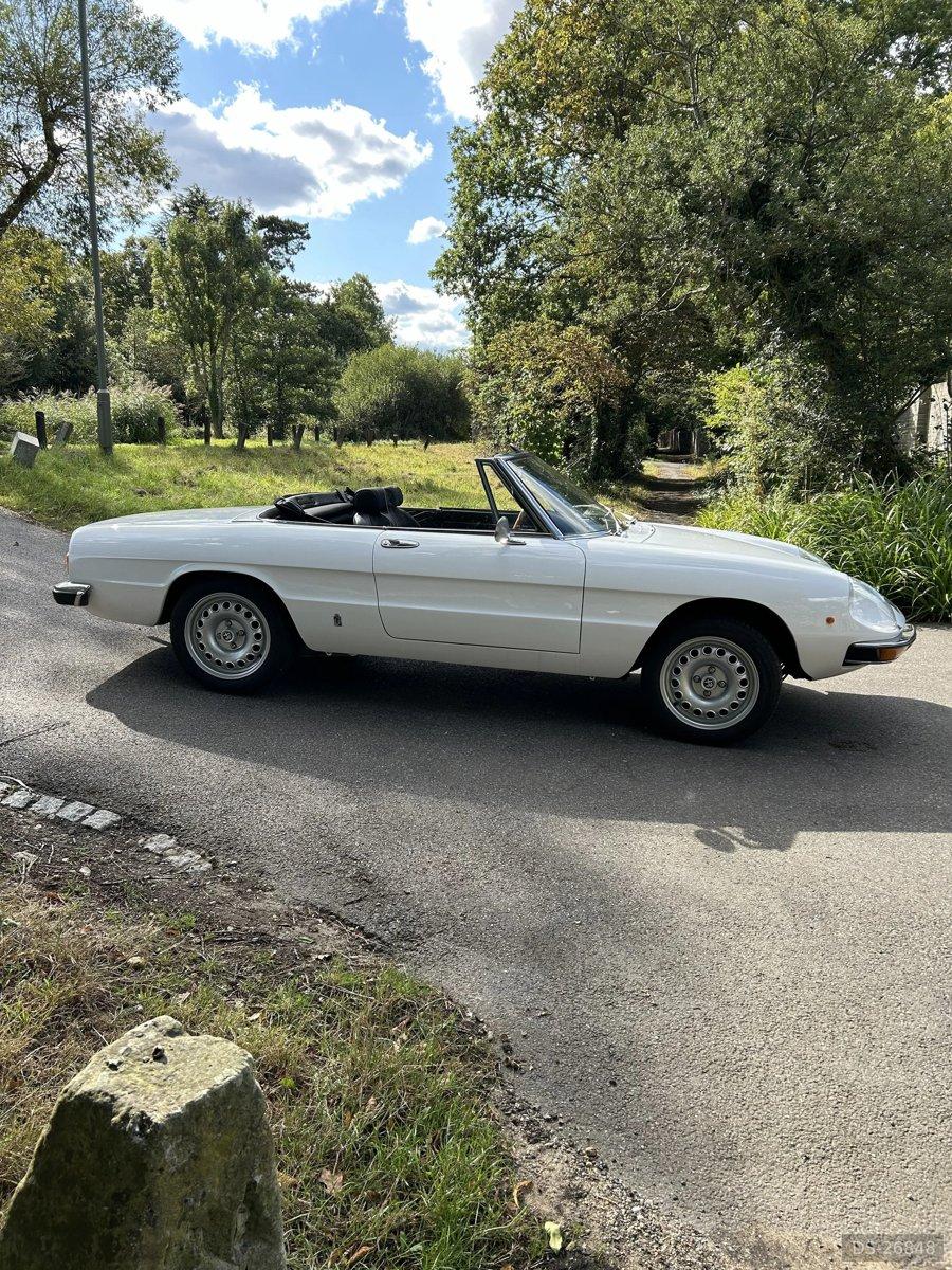 White Alfa Romeo Spider with the roof down on a country lane