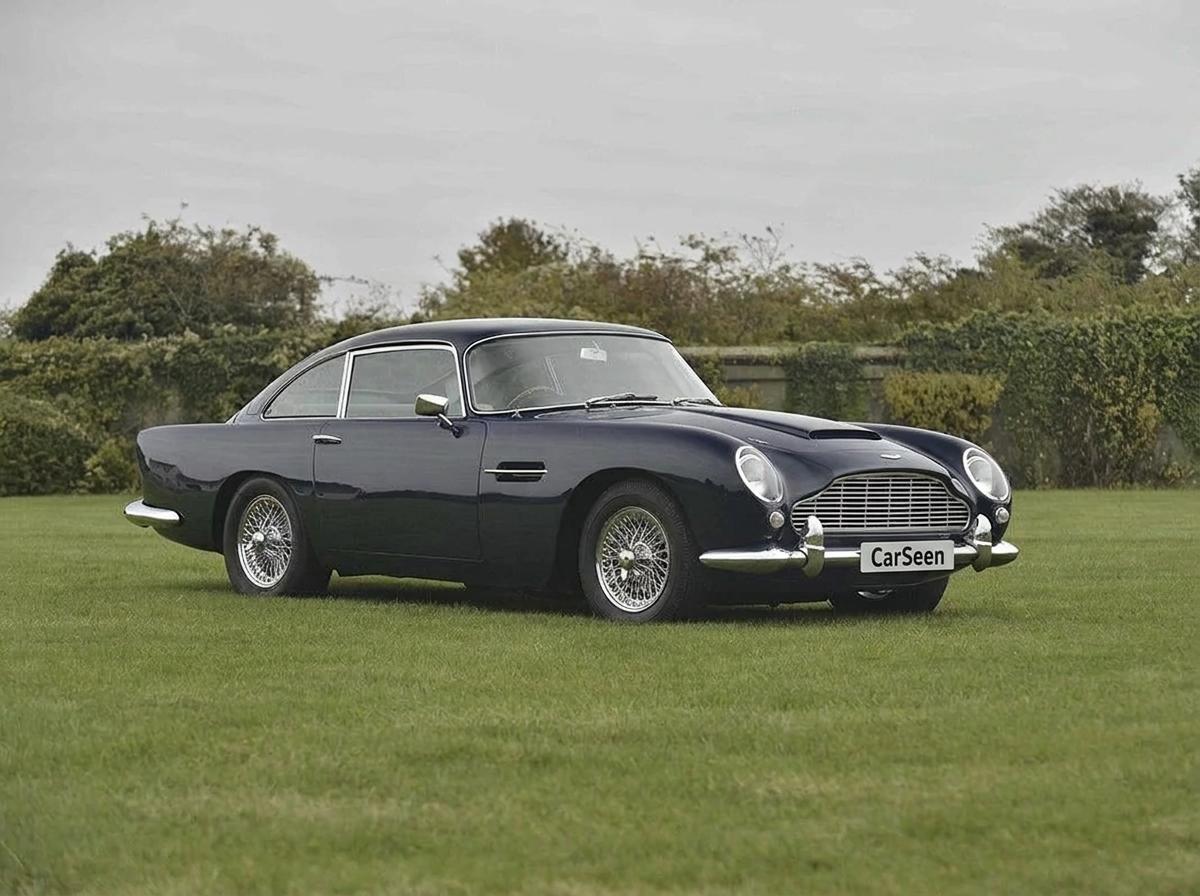 Deep grey Aston Martin DB5 on wire wheels in a green field near Surbiton