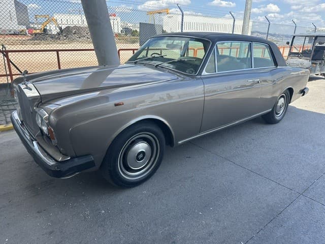 Bronze Rolls-Royce Corniche two-door saloon with black vinyl roof on a concrete forecourt