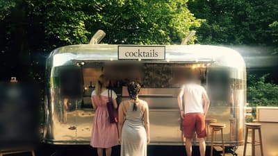Polished aluminium cocktail bar trailer with serving hatch open among trees