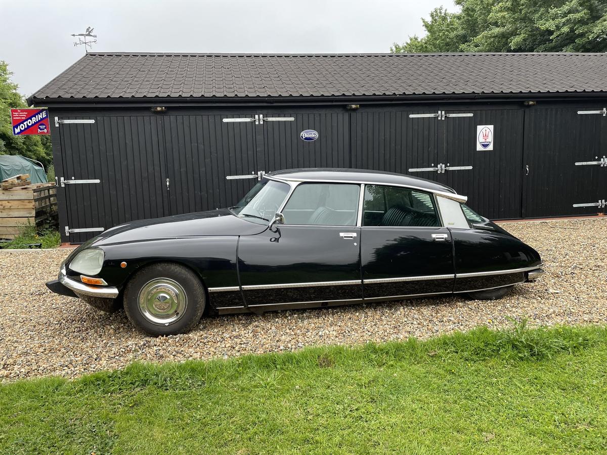 Black 1975 Citroën DS 23 Pallas in profile on gravel in front of a black timber garage
