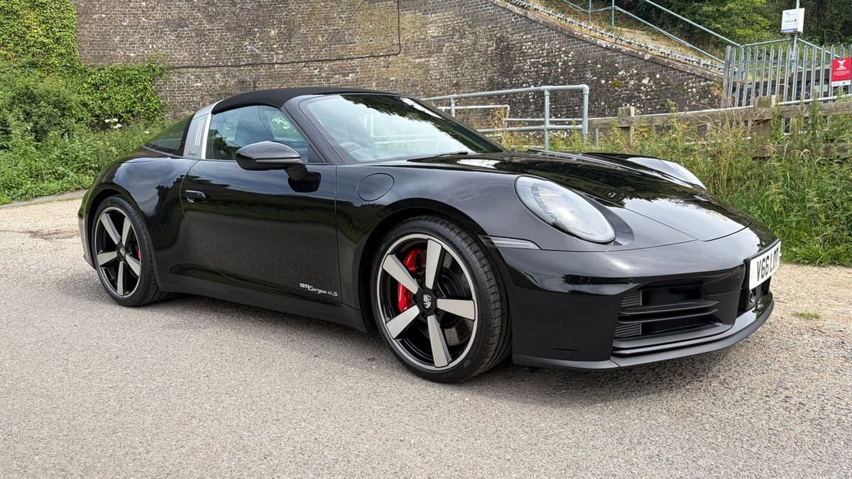 Black Porsche 911 Targa with red brake callipers beside a brick railway arch