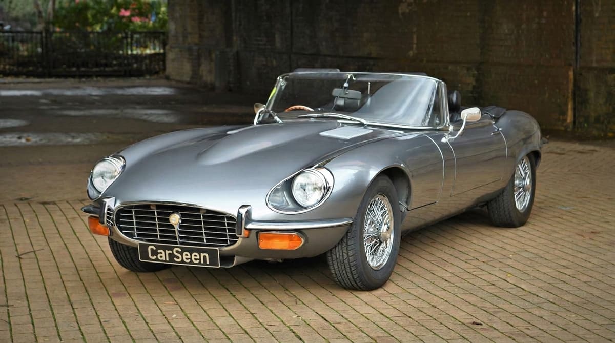 Silver Jaguar E-Type roadster beneath a stone arch