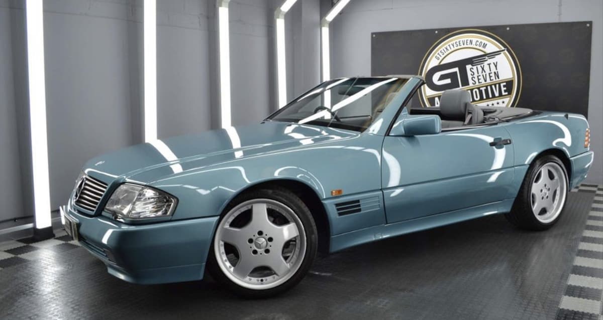 Teal Mercedes-Benz 500SL convertible with the roof down in a studio