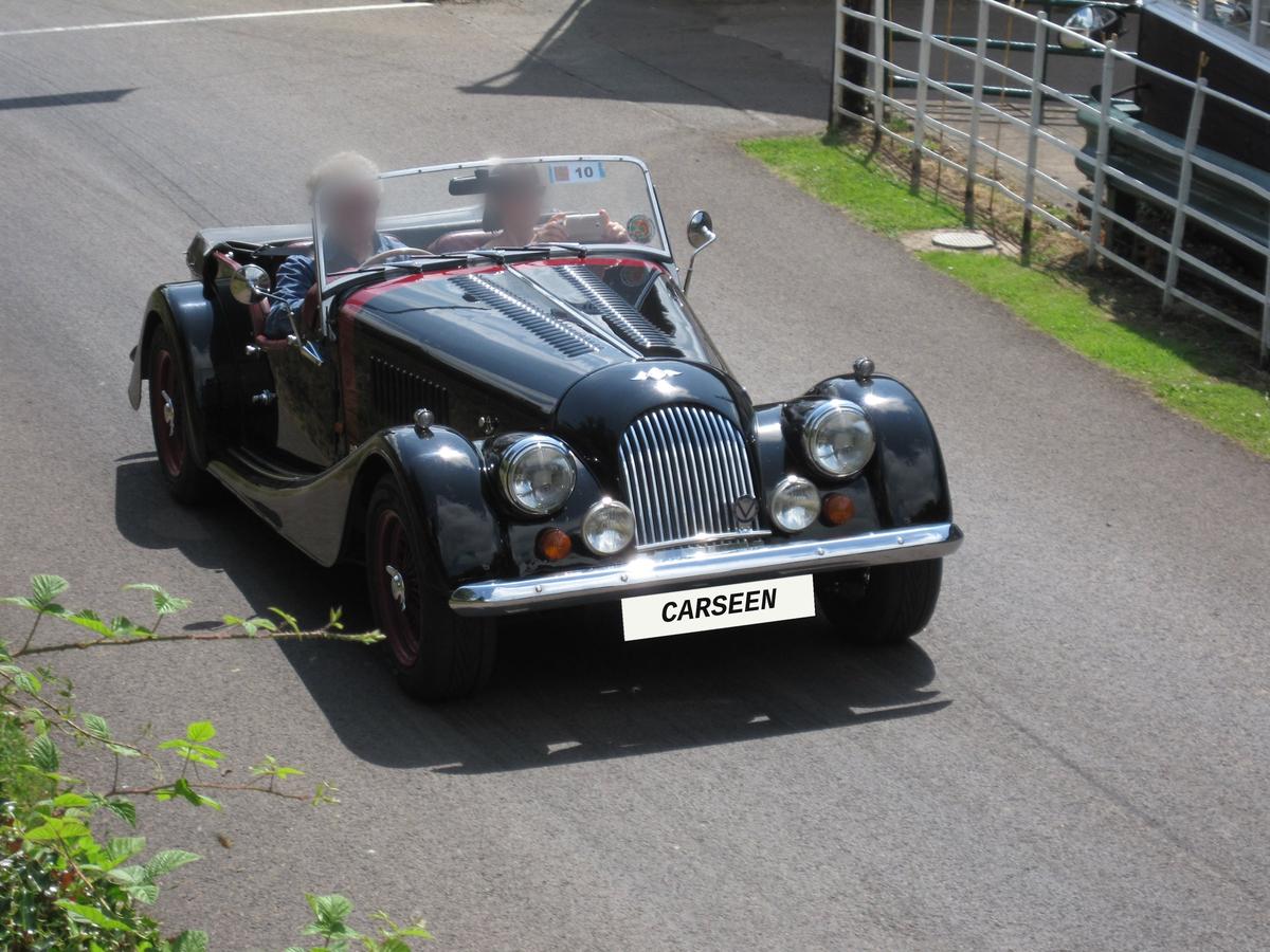 Black 1995 Morgan Plus 4 four-seater with the hood down and CarSeen plate on a country road