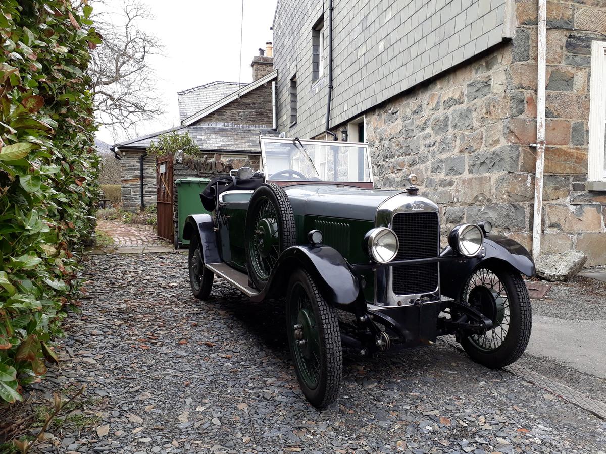 Green and grey 1929 Singer Junior Porlock open tourer on a slate courtyard beside a stone house