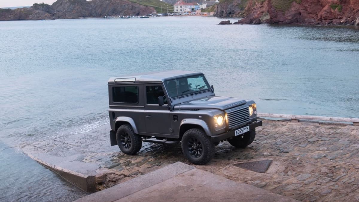 Grey Land Rover Defender 90 on a stone slipway at the water's edge