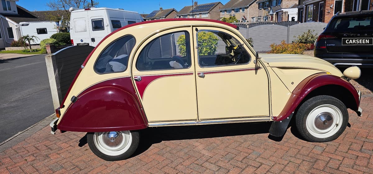 1986 Citroën 2CV Dolly in yellow and maroon, side profile on a brick driveway