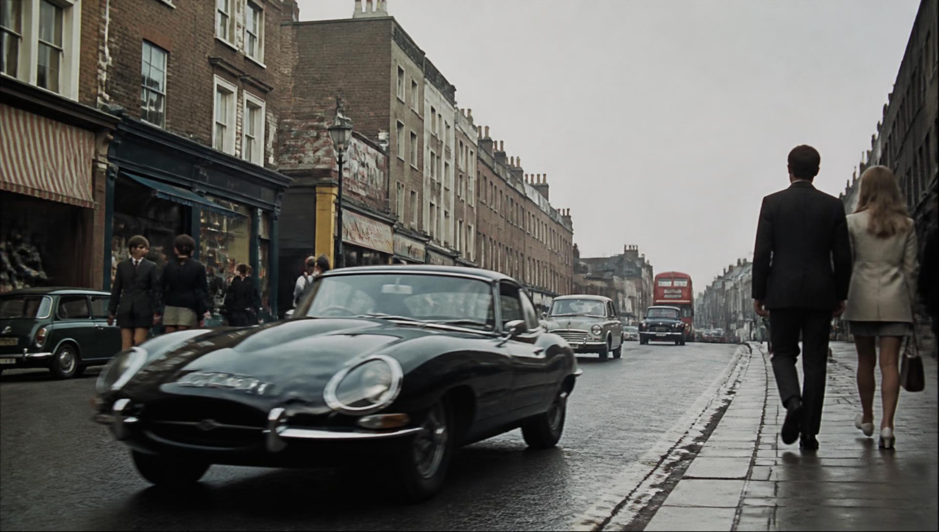 A black Jaguar E-Type passing through a Soho street in London, 1967